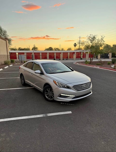White Hyundai Sonata sedan parked in empty lot at sunset