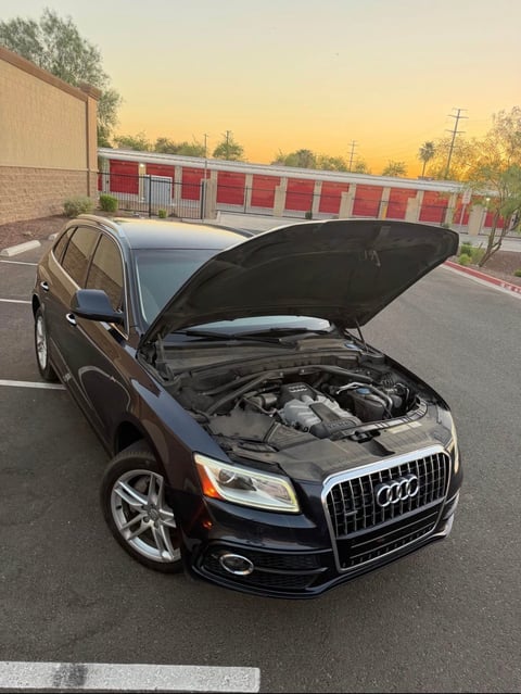 Black Audi Q5 SUV with open hood displaying engine at sunset