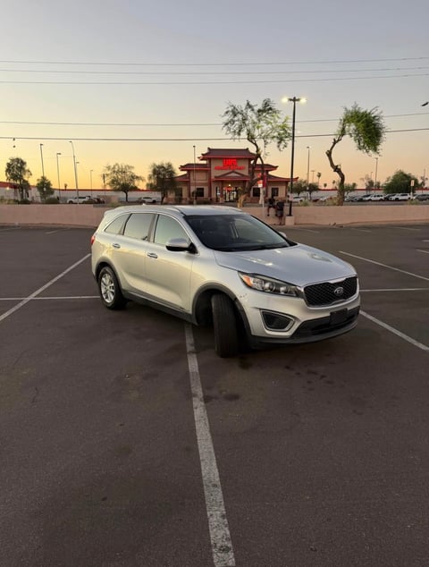 White Kia Sorento SUV parked in empty parking lot at dusk with commercial buildings