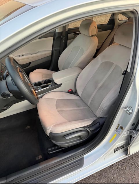 Interior view of a silver car with beige and gray cloth seats