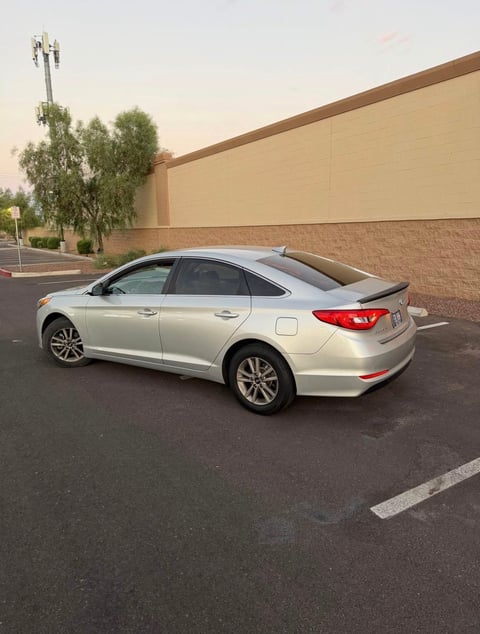 Silver sedan parked in a parking lot in front of a tan brick building