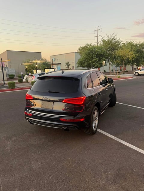 Black Audi Q5 SUV parked in empty lot at sunset