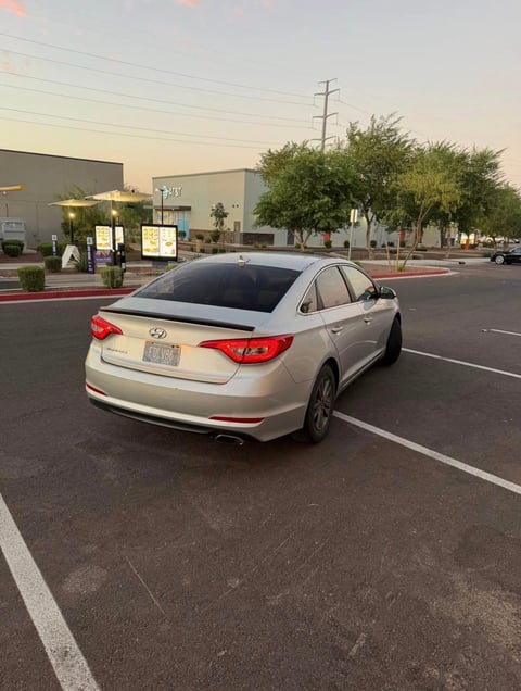 Silver Hyundai Sonata sedan parked in an empty parking lot at dusk