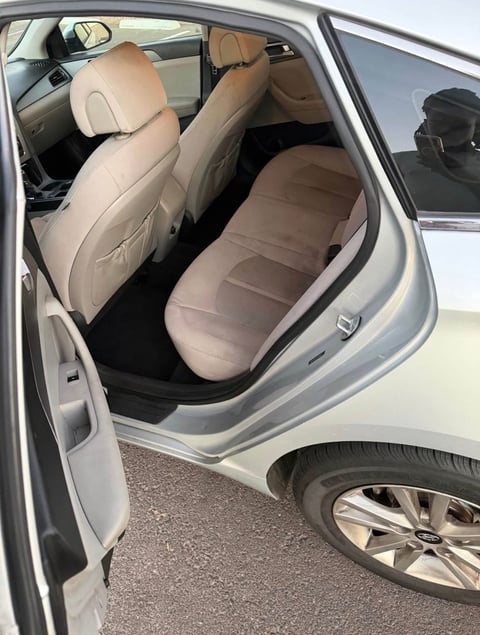 Interior view of a car with open door showing tan leather seats and dashboard