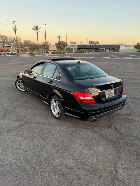 Black Mercedes-Benz sedan parked in an empty parking lot at dusk