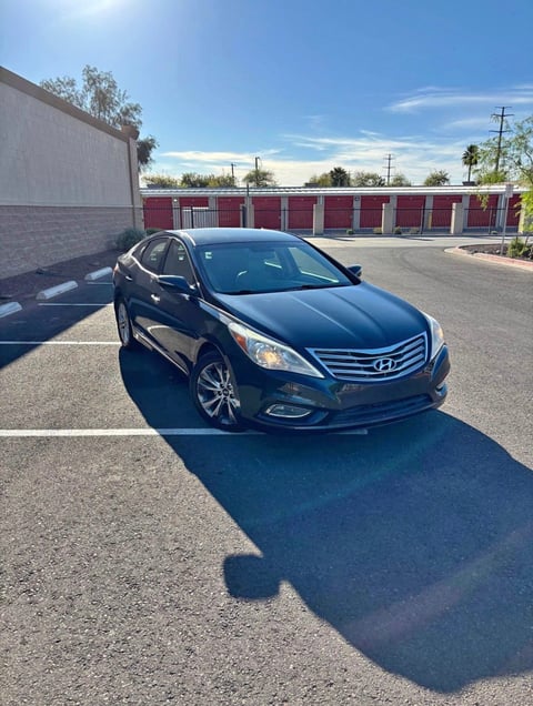 Black Hyundai Sonata sedan parked in lot with red storage units and clear blue sky in background