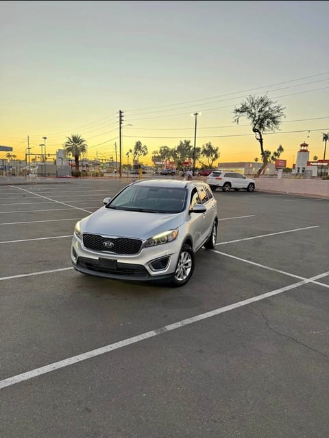 White Kia Sorento SUV parked in empty parking lot at sunset