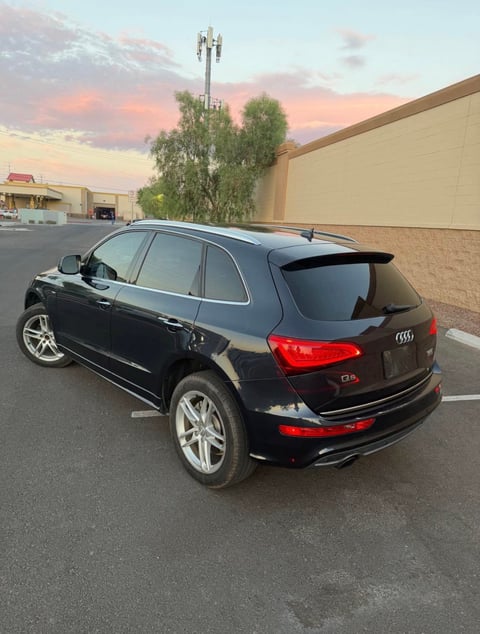 Black Audi Q5 SUV parked in a lot at sunset with buildings and trees