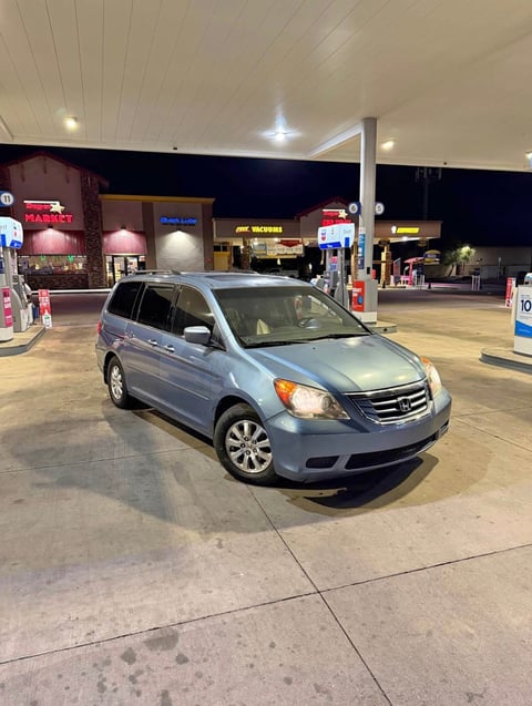Silver Honda Odyssey minivan parked at a gas station at night