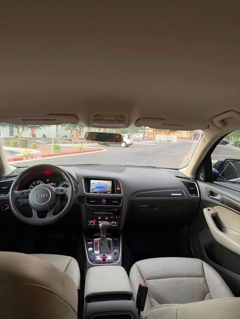 Interior view of Audi car dashboard, steering wheel, and beige leather seats